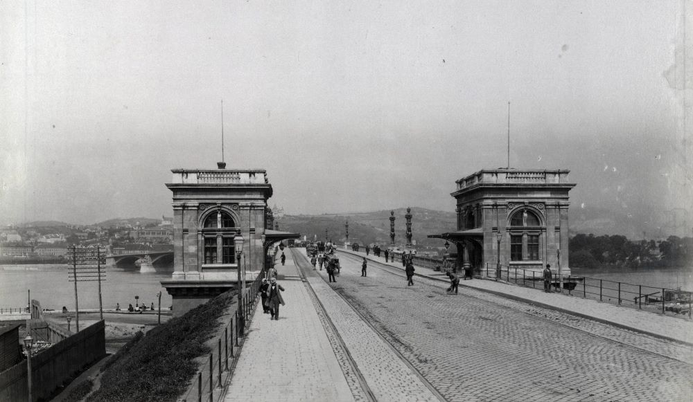 A Margit híd pesti hídfője a vámházakkal 1890–1894 között. Távolban a budai hídfő felett látható a Gül Baba türbéje köré épített Wagner villa.