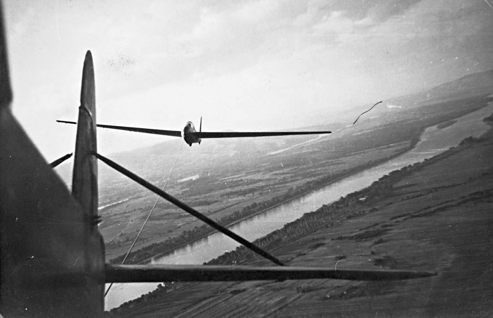 Egy motoros Mráz K-65 (Fi-156) vontat egy LF-107 Lunak vitorlázó műrepülőgépet Dunakeszi felett az 1950-es évek első felében. A fényképezés népszerű volt a pilóták körében, bár voltak olyan idők is, amikor a versenyek kivételével tilos volt a magasból felvételt készíteni.